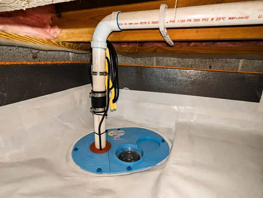 Crawl space sump pump and discharge pipe set in a basin under a vapor barrier
