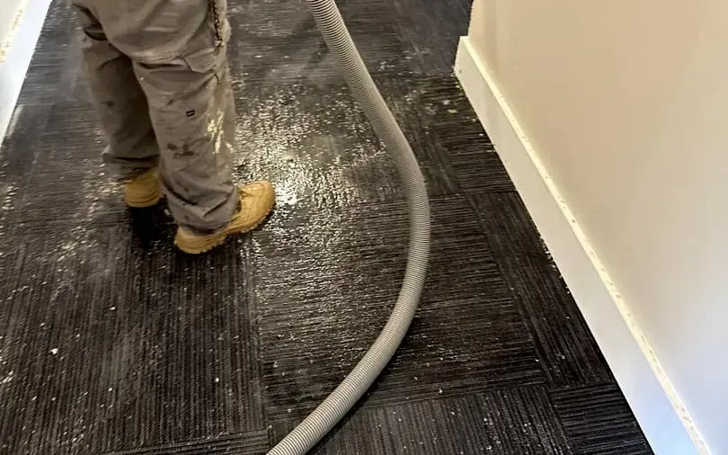 Extraction hose pulling standing water off wet carpet during a water damage cleanup in Matthews, NC